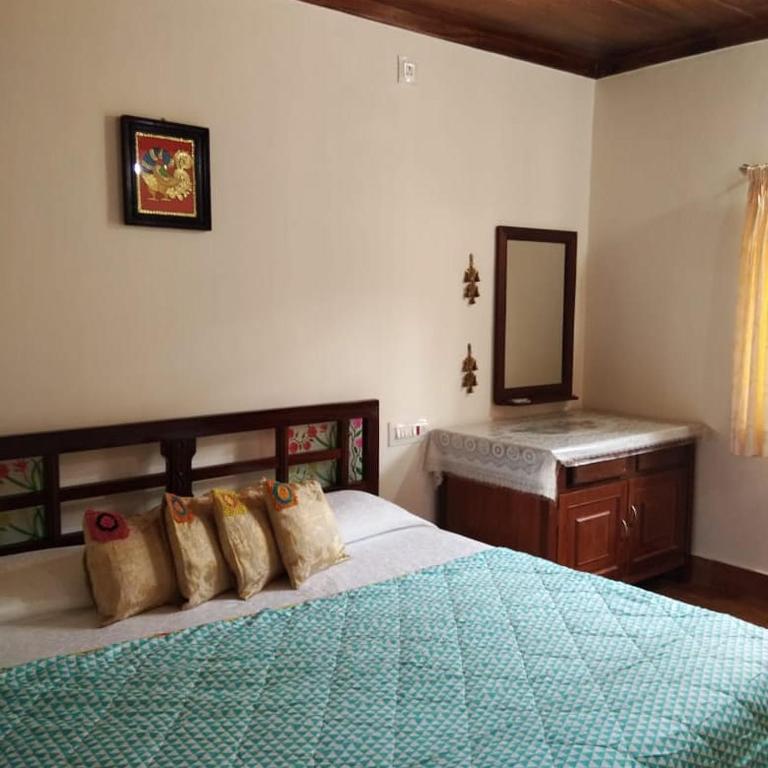 a bedroom with a bed and a vanity and a mirror at Krushikoota Homestay in Sringeri