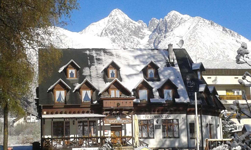 ein Haus vor einem schneebedeckten Berg in der Unterkunft Penzión Encián in Tatranská Lomnica