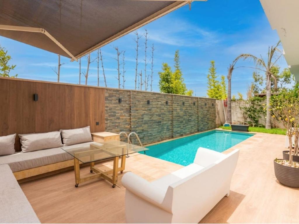 a swimming pool with a couch and a table at Villa Séréna Pool and Comfy in Tamaris