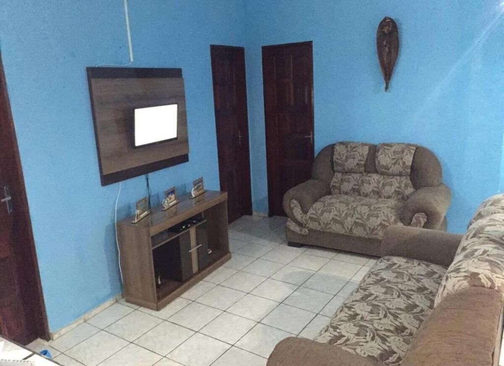 a living room with a couch and a flat screen tv at Casinha de vó in Aracati