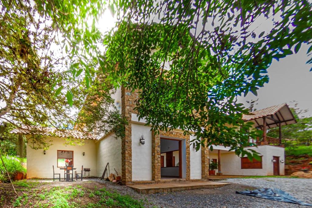 a white house with trees in front of it at Casa de Teja Barichara in Barichara