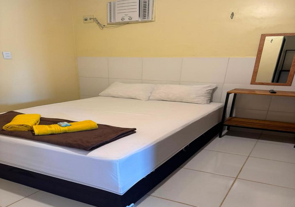 a white bed with a brown blanket and a mirror at Figueiredo Hosp 2 in Presidente Figueiredo