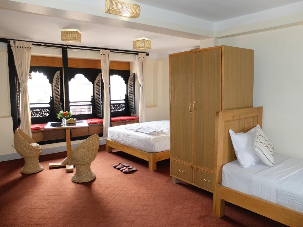 1 dormitorio con 2 camas, mesa y sillas en Lalit Heritage Home en Pātan