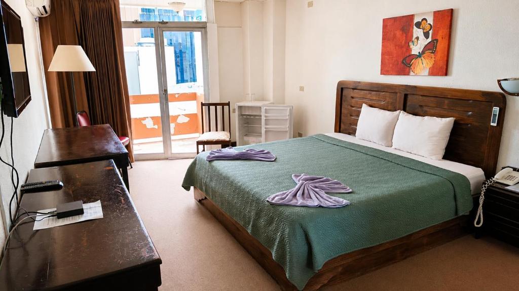a hotel room with a bed with a green blanket at Hotel Maragato in San José