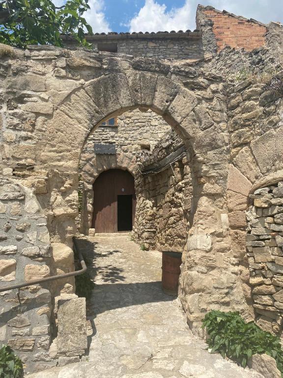 a stone building with an archway and a door at Cal Rabell in Bellmunt