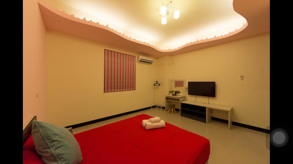 a bedroom with a red bed and a desk with a television at Kenting Orange Homestay in Hengchun