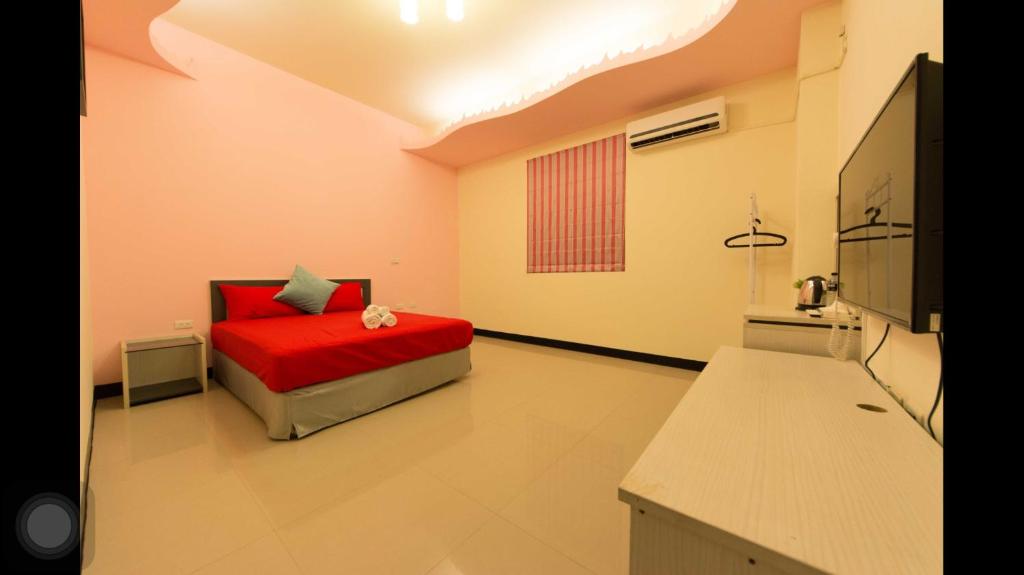 a bedroom with a bed with a red blanket at Kenting Orange Homestay in Hengchun