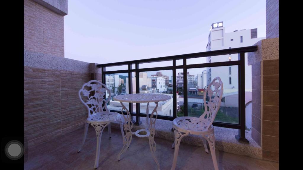 a balcony with a table and two chairs and a window at Kenting Orange Homestay in Hengchun