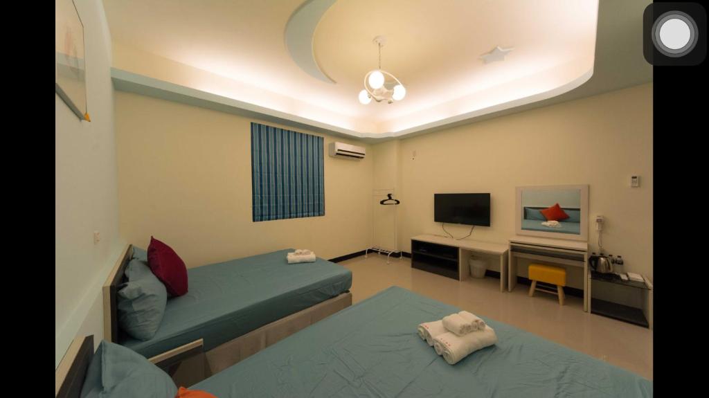 a room with a bed and a desk and a television at Kenting Orange Homestay in Hengchun
