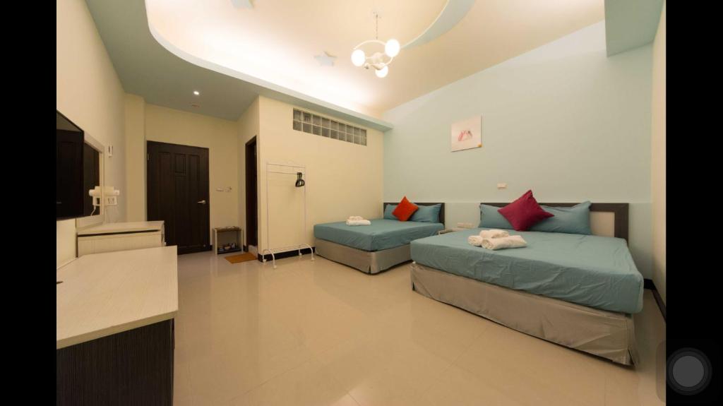 a bedroom with two beds and a television in it at Kenting Orange Homestay in Hengchun