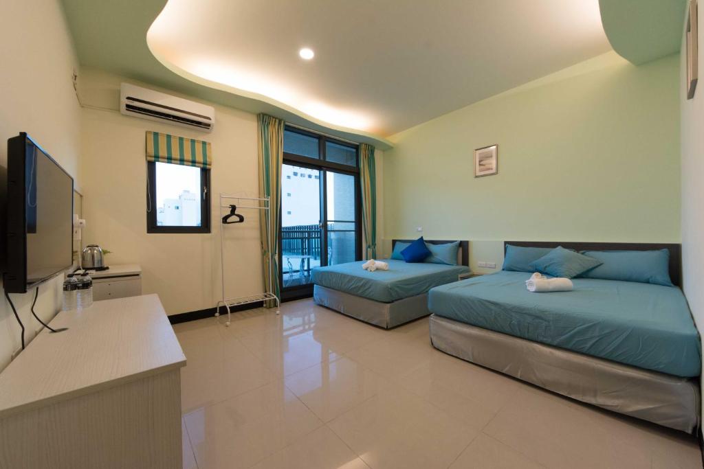 a bedroom with two beds and a flat screen tv at Kenting Orange Homestay in Hengchun
