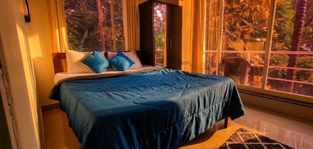 a bedroom with a bed with blue sheets and a window at GS Home on the Bay - Sea & forest view glass studio in Vagator