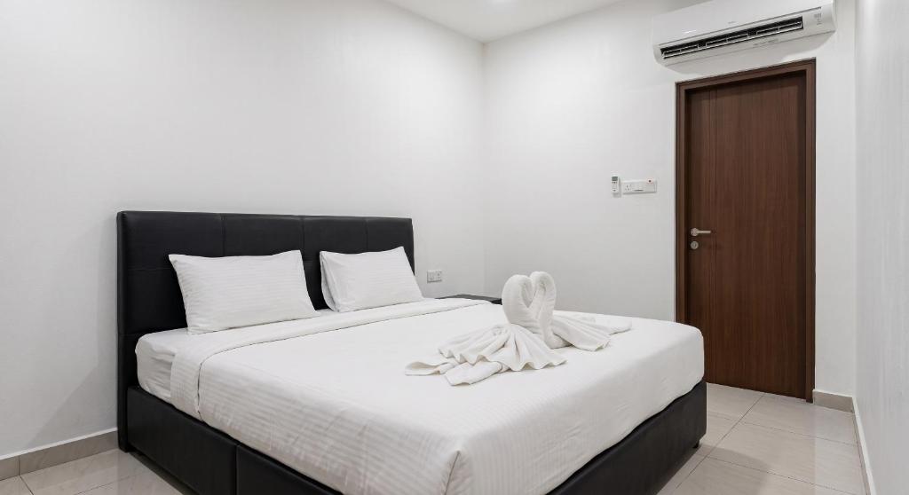 a bed with a black headboard and white sheets at Swing & Pillows - Kuala Selangor in Kuala Selangor