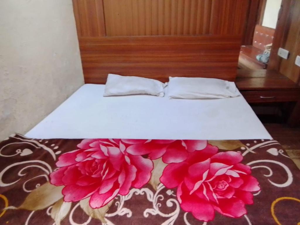 a bed with two pillows and pink flowers on it at Hotel shree in Indore