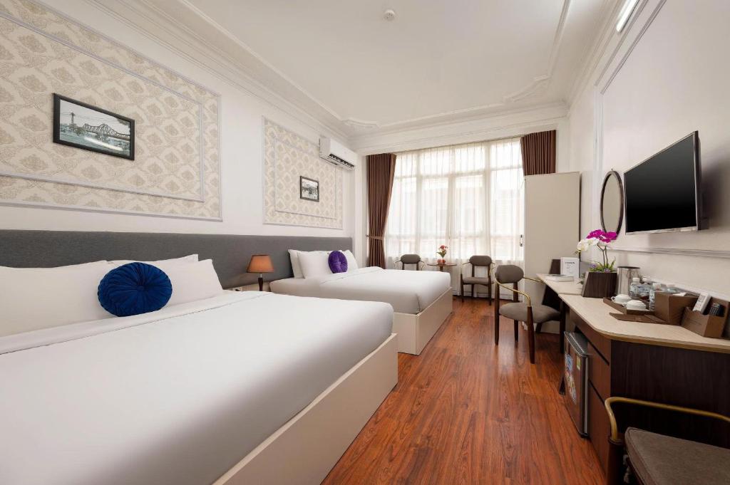 a hotel room with two beds and a desk at The Lake Silk Hotel & Travel in Hanoi
