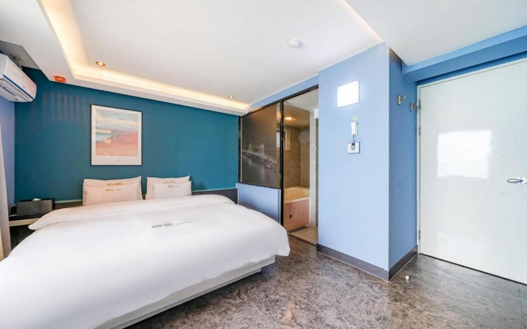 a bedroom with a large bed and a blue wall at Busan Gwangalli SEAYOU HOTEL in Busan