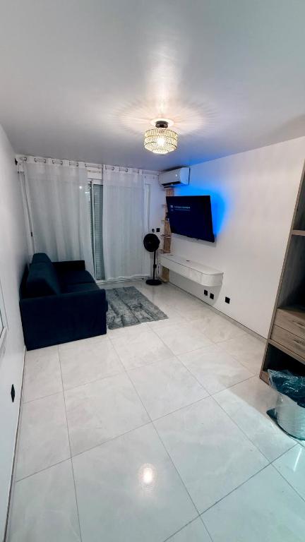 a living room with a couch and a flat screen tv at Studio cosy Ducos in Ducos
