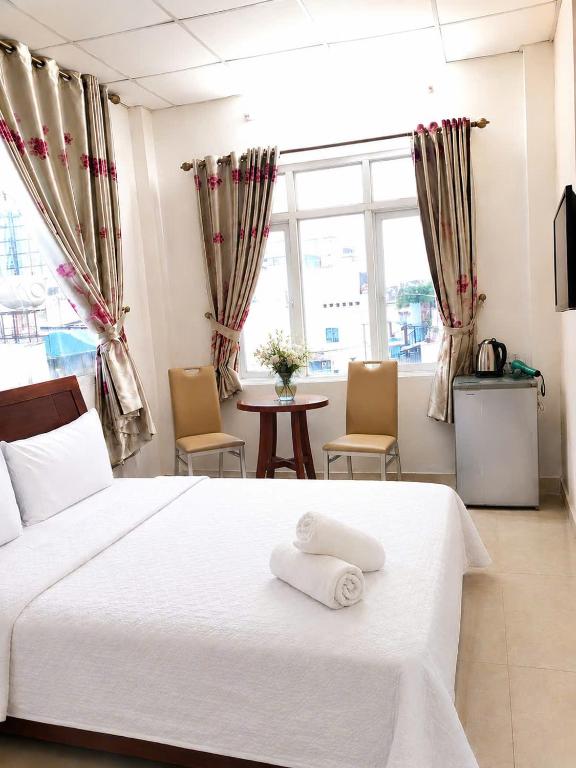 a bedroom with a white bed with two chairs and a table at Thanh Ha Guesthouse in Ho Chi Minh City