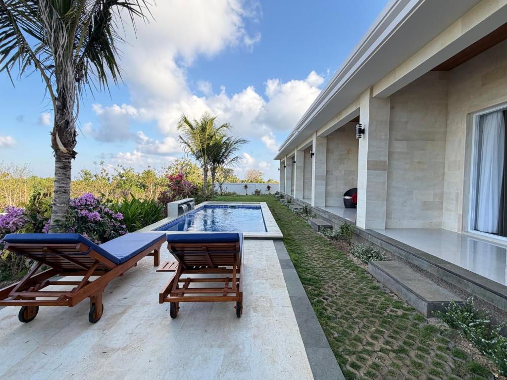 a patio with two chairs and a swimming pool at Bunut Sari Guesthouse in Ungasan