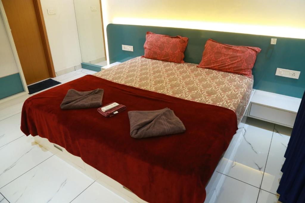 a bedroom with a large bed with red sheets and red pillows at The Crownstone Apartment in Trivandrum