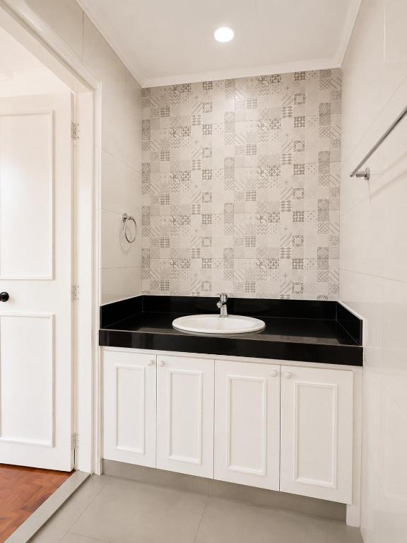 a bathroom with a sink and a black counter at Trip Nest Homestay in Manila