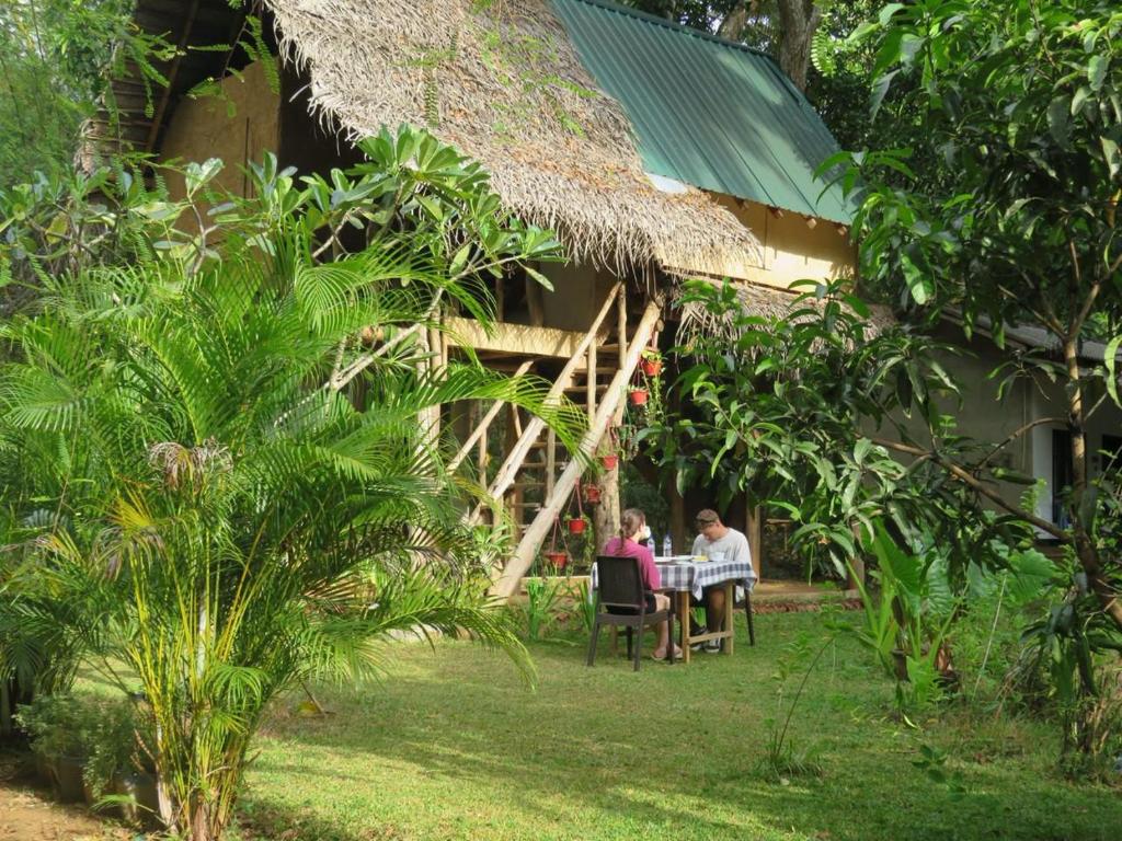 two people sitting at a table in front of a house at Sigiri Veenus Tree House in Sigiriya
