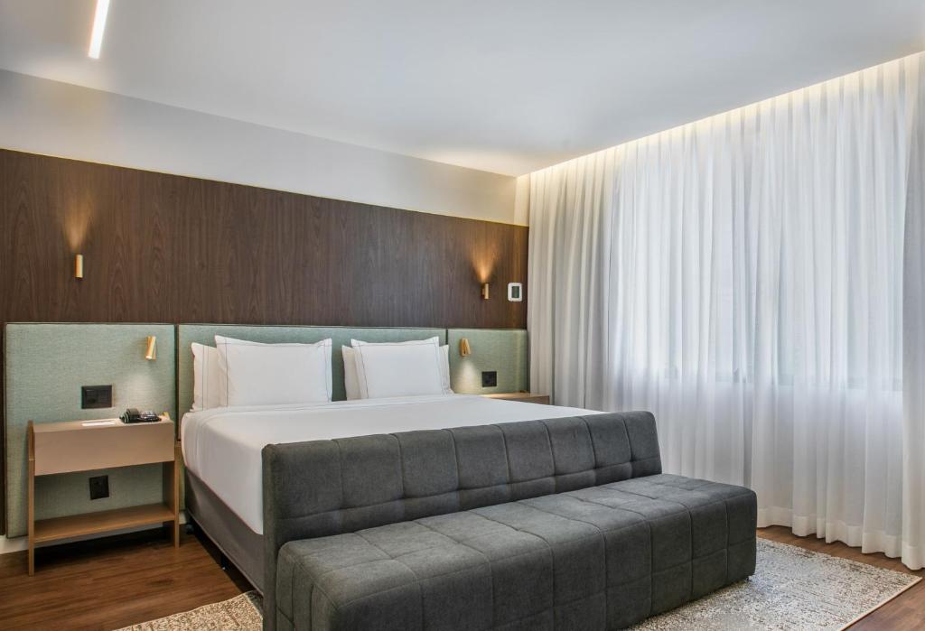 a bedroom with a large bed and a couch at Meliá Paulista in São Paulo