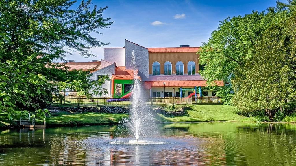 a fountain in the middle of a pond in front of a building at Hotel Cheribourg, an Ascend Collection Hotel in Magog-Orford