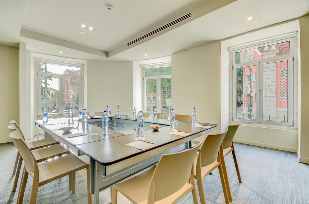 A small meeting room with a central table, pale chairs and street-facing windows.
