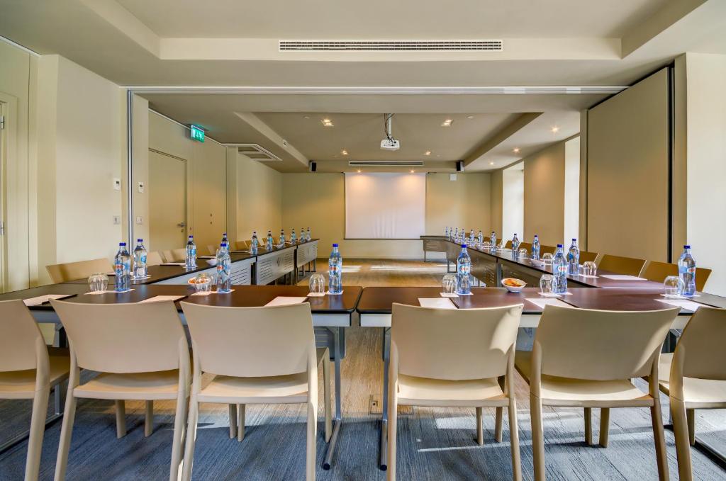 A long conference setup viewed from the rear, facing a projection screen.