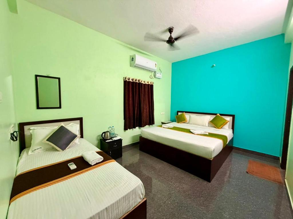 two beds in a room with blue and green walls at De Quite Villa in Pondicherry