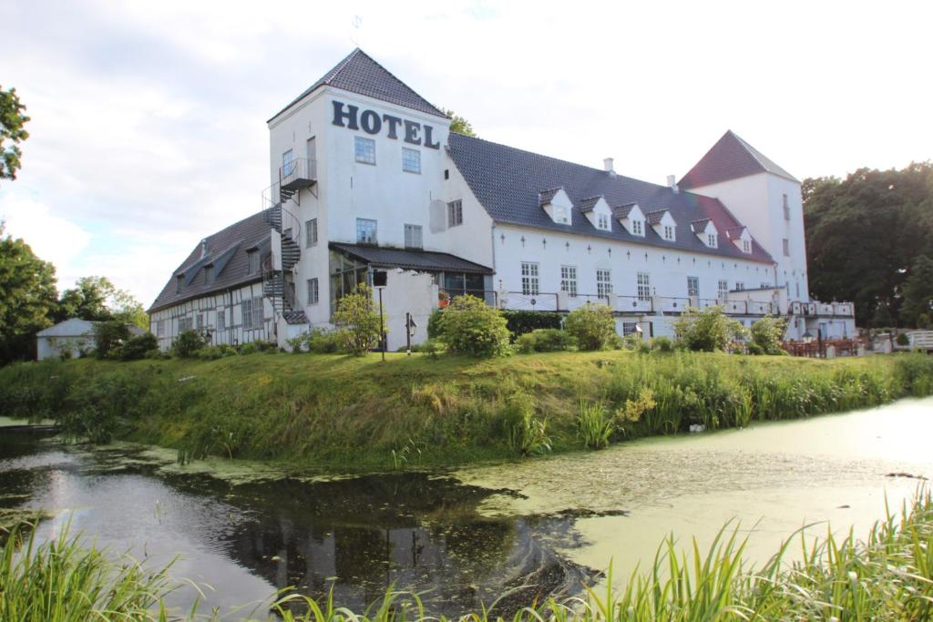 un hotel en una colina junto a un río en Vraa Slotshotel, en Tylstrup