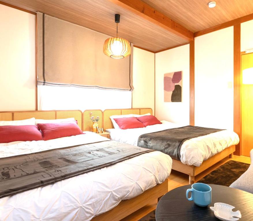 a bedroom with two beds and a table and a window at casa de tsuru in Osaka