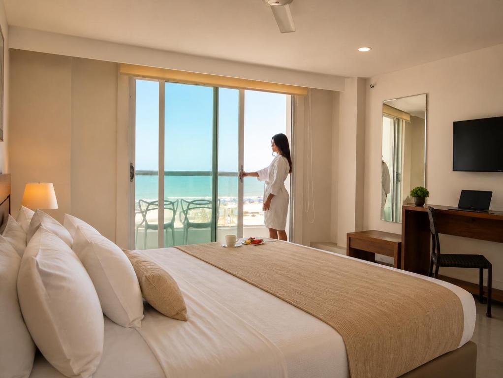a woman standing in a hotel room looking out the window at Hotel Summer Frente Al Mar in Cartagena de Indias
