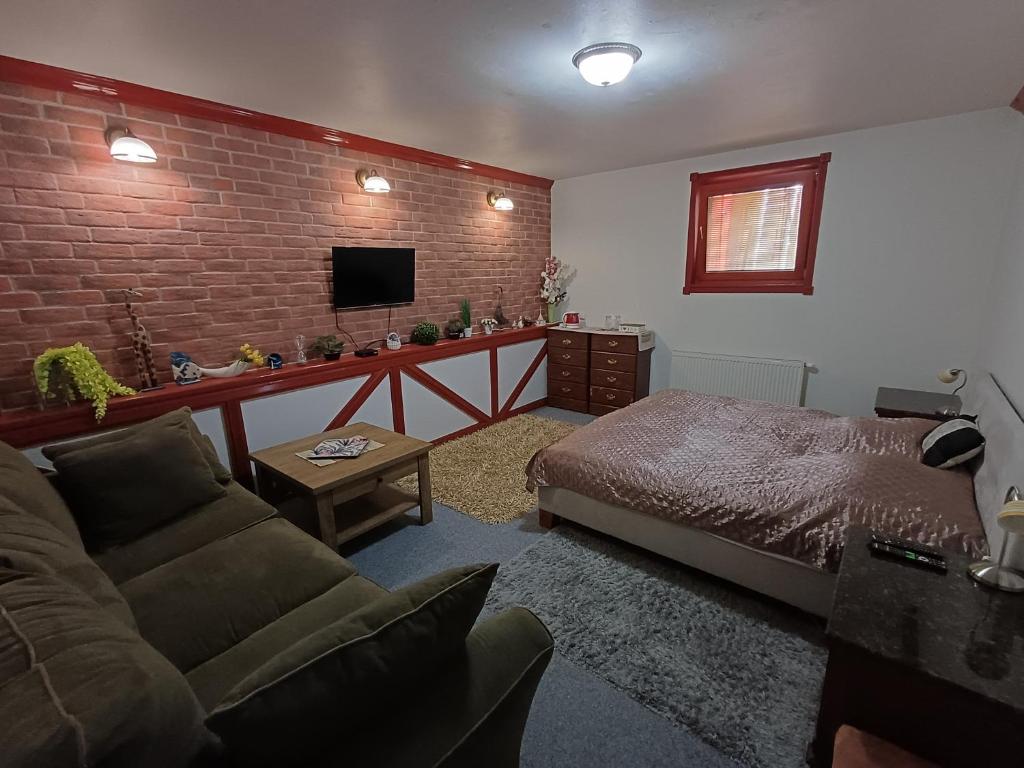 a living room with a bed and a brick wall at Izba v centre in Bardejov