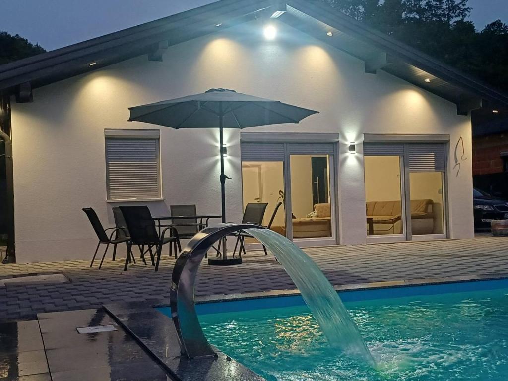 a pool with an umbrella next to a house at Villa Una Verde in Bosanska Krupa