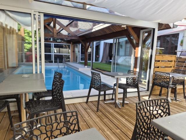 a patio with a table and chairs and a pool at Hotel De Paris in Poligny
