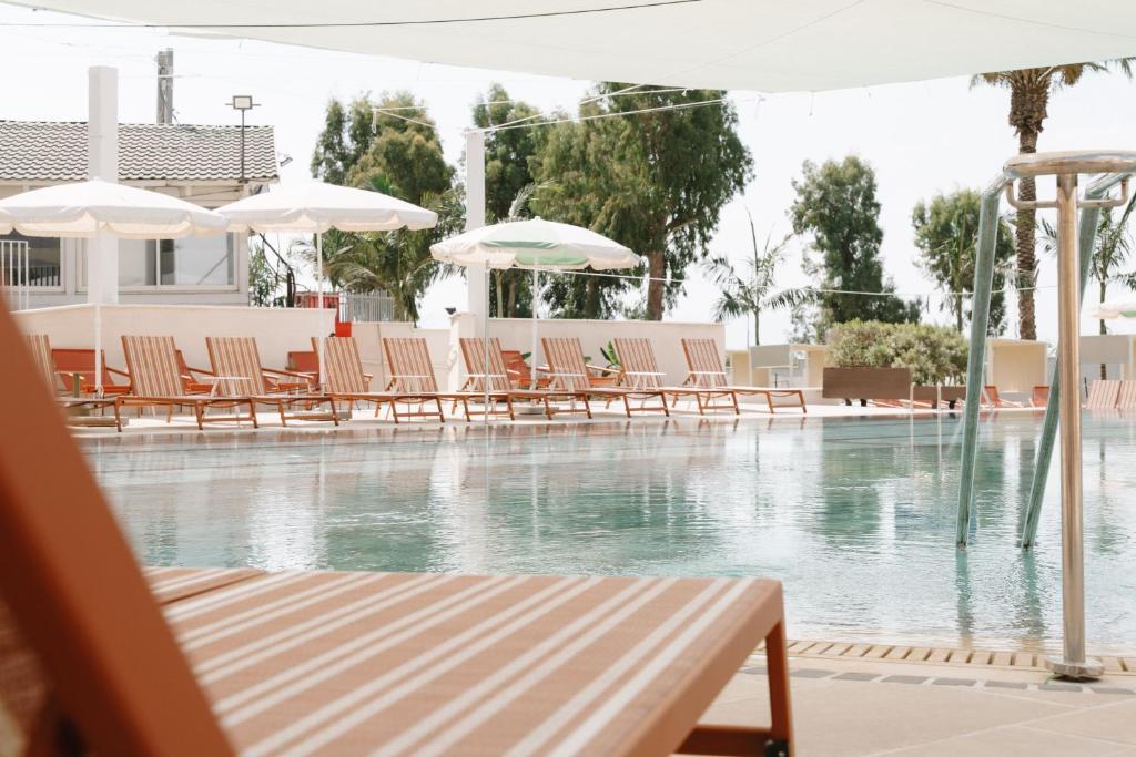 a pool of water with chairs and umbrellas at Nof Ginosar Kibbutz Hotel in Kibbutz Ginnosar