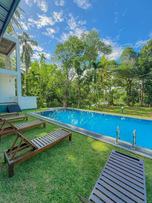 a pool with two benches next to a house at Nilwadula Hotel Udawalawe in Ratkarawwa