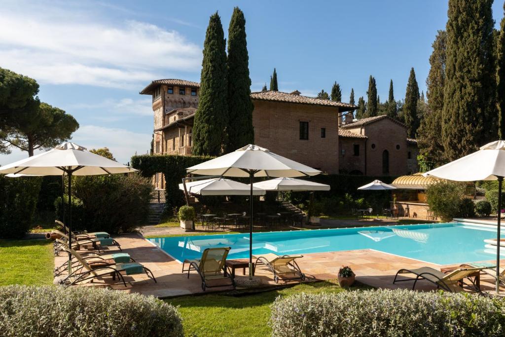 a pool with chairs and umbrellas in front of a building at Hotel La Collegiata - Adults Only in San Gimignano