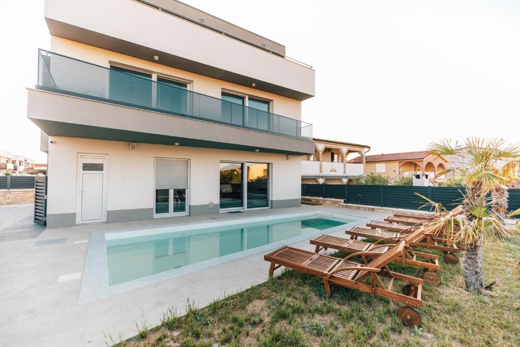 a house with a swimming pool and some lounge chairs at Villa Aura Vir in Vir