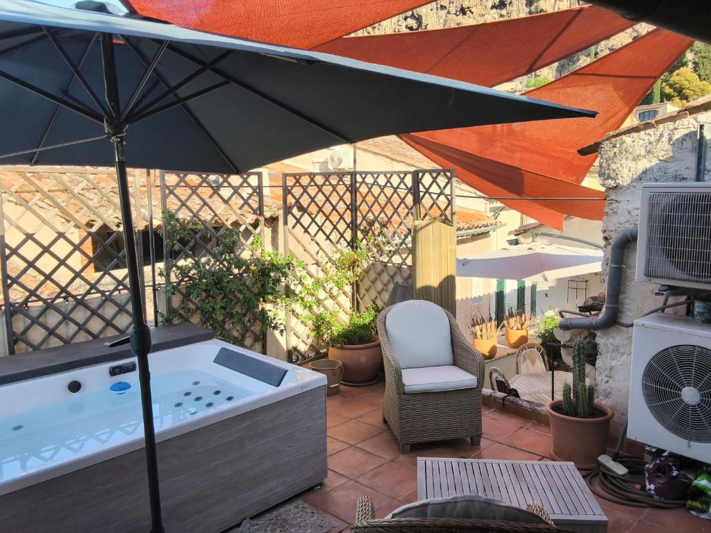 a hot tub with an umbrella on a patio at Le bateau sur les toits in Cotignac