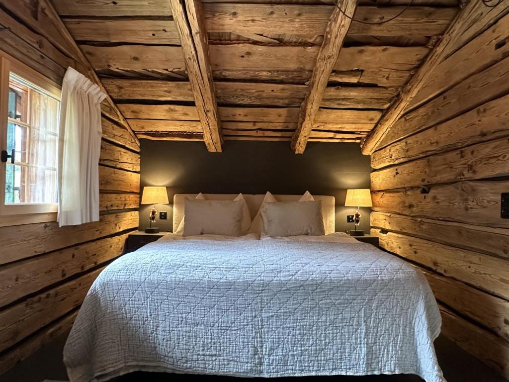 ein Schlafzimmer mit einem Bett in einer Holzwand in der Unterkunft Heidi's Hideout - Private historic chalet by Heiti Gstaad in Gstaad