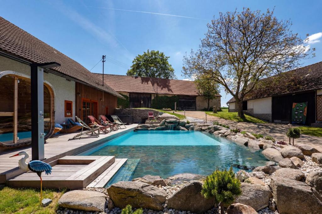a swimming pool with rocks in a backyard at WELLNESS FARMHOUSE Monínec in Měšetice