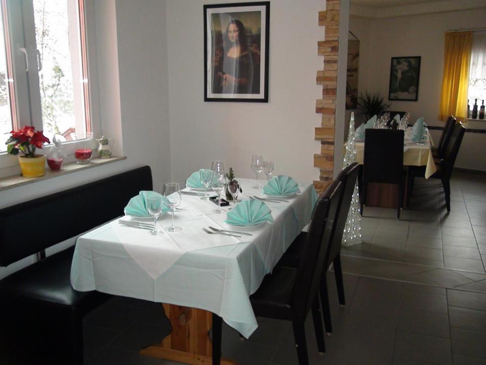 mesa de comedor con mantel y sillas blancas en Fino da Mario, en Ebersbach an der Fils