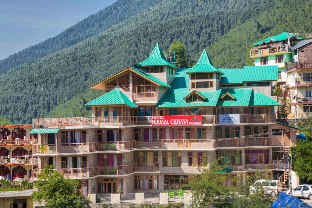 a large building with green roofs on a mountain at Hotel Nirmal Chhaya in Manāli