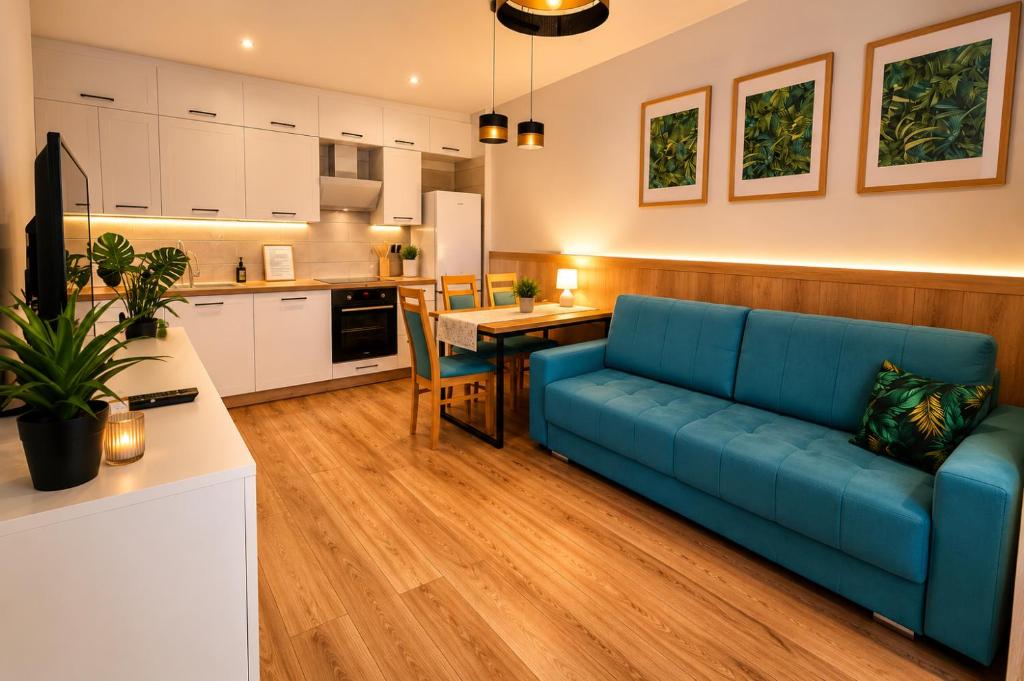 a living room with a blue couch and a kitchen at Szmaragdowa Przystań - apartament z parkingiem blisko Parku Zdrojowego i Tężni in Busko-Zdrój