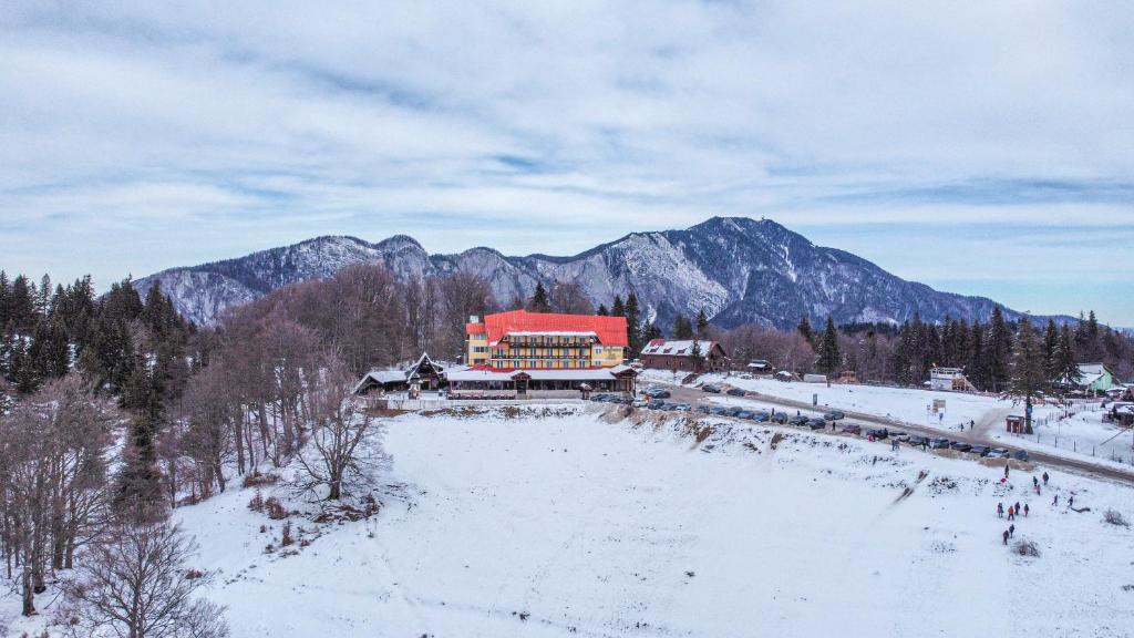 a large building with a red roof in the snow at Cabana Trei Brazi in Predeal