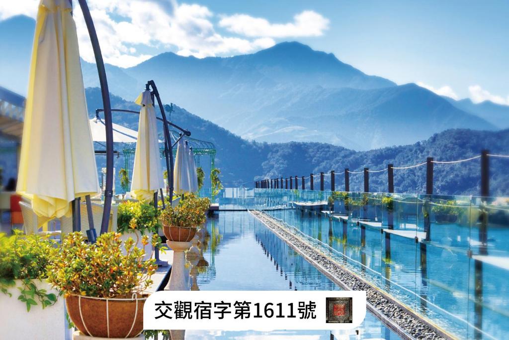 a pool with umbrellas and potted plants and mountains at Fleur de Chine Hotel in Yuchi