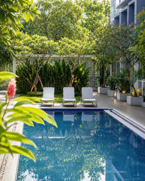 two chairs sitting next to a swimming pool at The Rooms Apartment Bali by ARM Hospitality in Denpasar